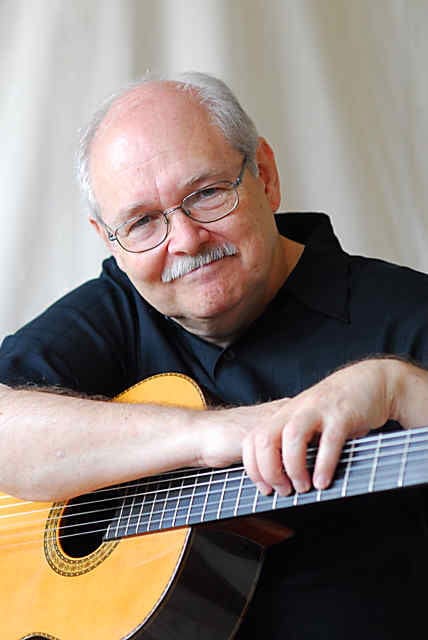 John Knowles, CGP, holding an acoustic guitar